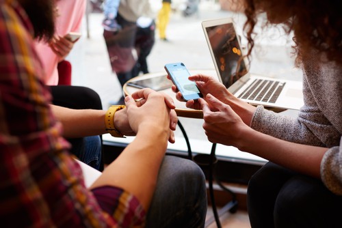 two friends look at a social media post on their phone